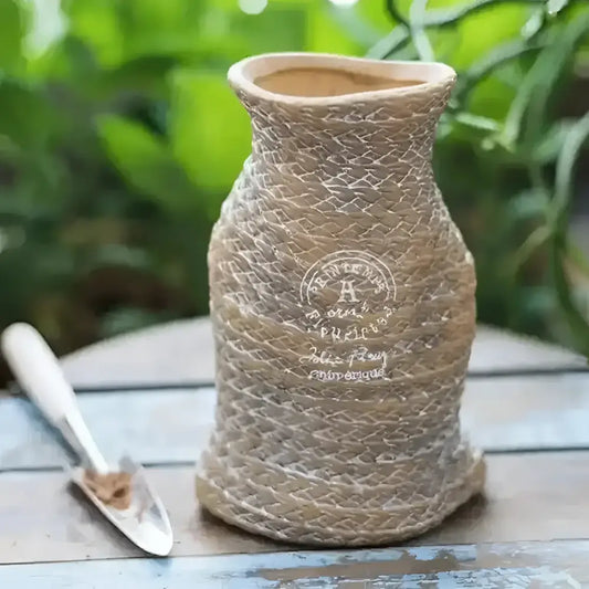 A vase shaped small planter with a woven bag shape and design