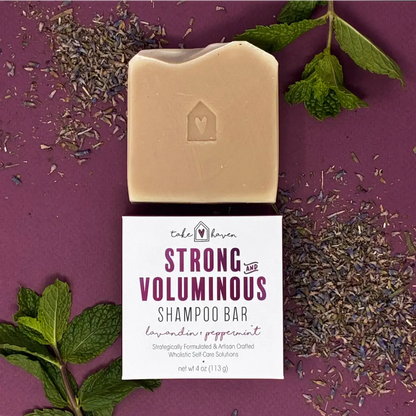 A beige rectangular herbal shampoo bar infused with nourishing organic oils sits on its branded packaging