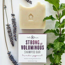 Cream-colored herbal shampoo bar with heart cutout on box labeled strong and voluminous infused with nourishing organic oils