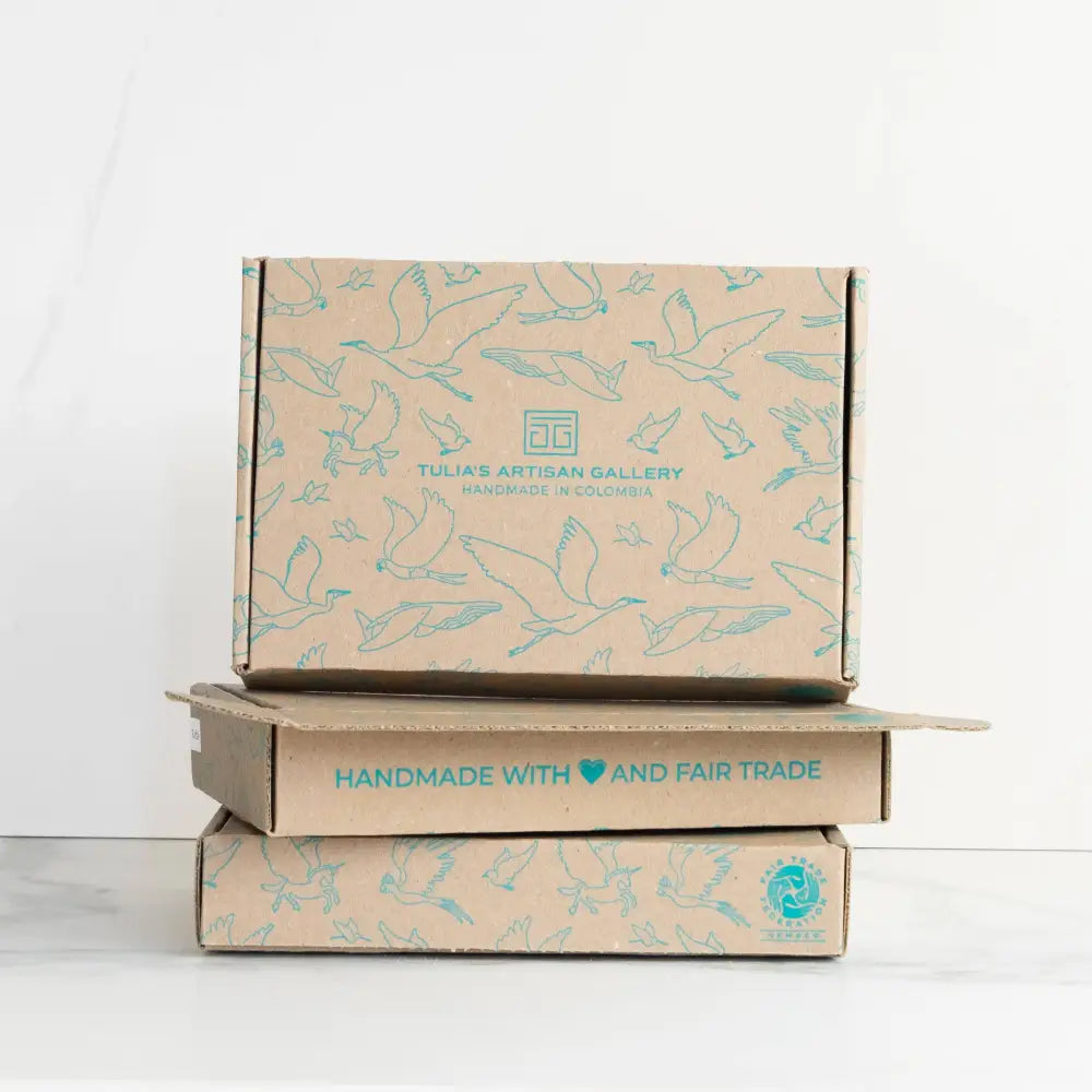 Stack of three brown cardboard boxes with light blue bird art from tulia’s artisan gallery woman-owned eco-friendly handmade