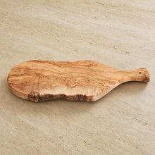 Italian olivewood cutting board with live bark edge paddle handle and natural wavy grain pattern