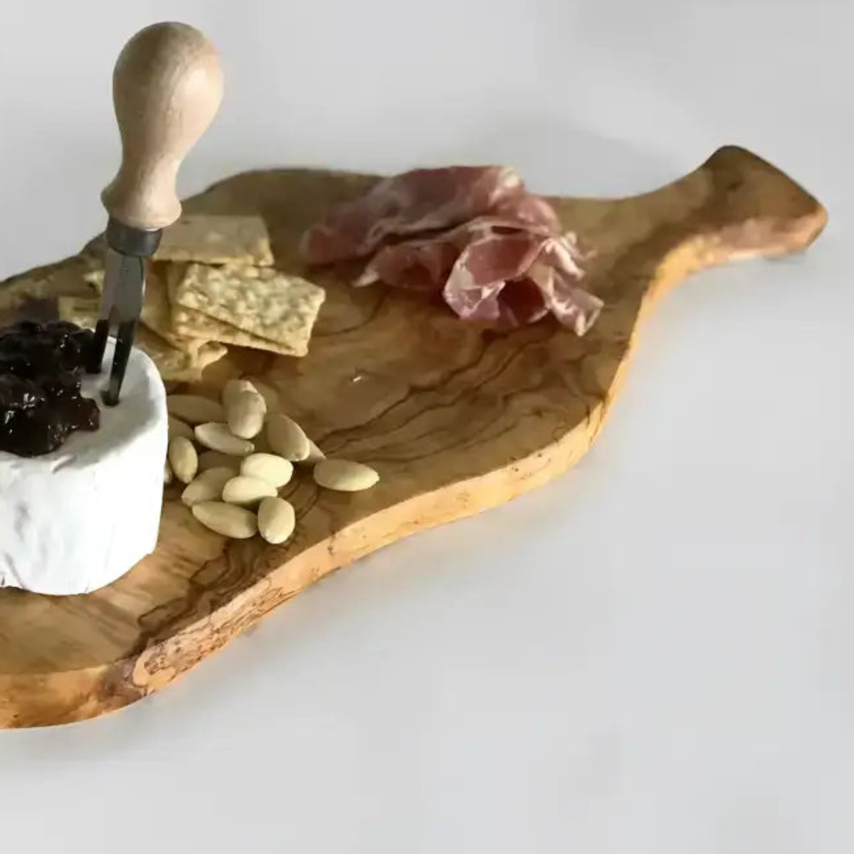 Natural italian olivewood cutting board with live bark edge, irregular shape, visible grain, and paddle handle