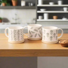 Three white leafy green stoneware mugs with gray botanical patterns for a cozy vibe