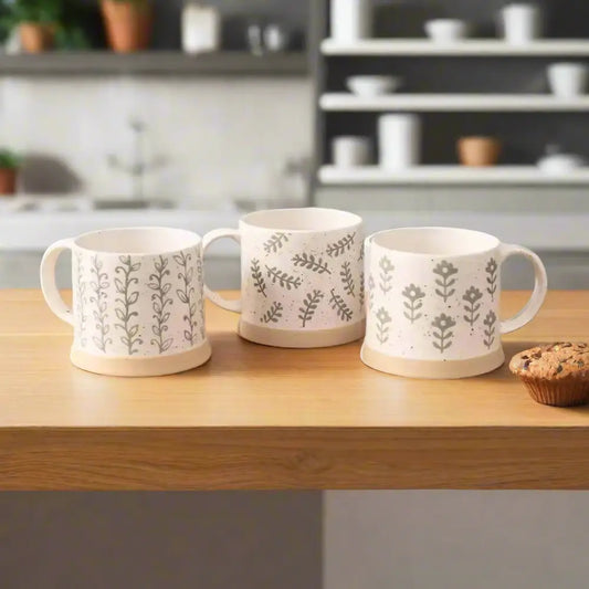 Three white leafy green stoneware mugs with gray botanical patterns for a cozy vibe