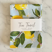 A soft light blue pure cotton handmade tea towel with bright yellow lemons green leaves and white blossoms