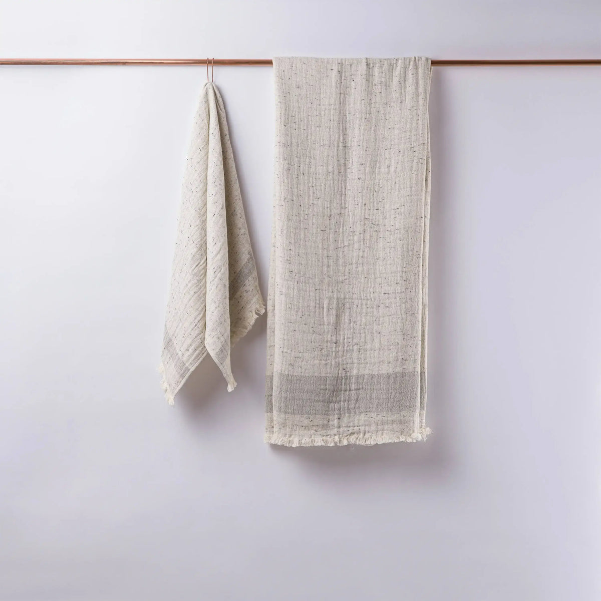 Textured off-white linen towels hanging on copper rod, perfect as double-layered muslin bath towels in Cotton Nope Yarn
