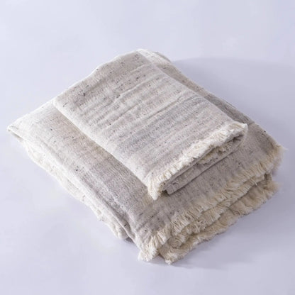 Two folded light-colored fringed muslin bath towels made from cotton nope yarn