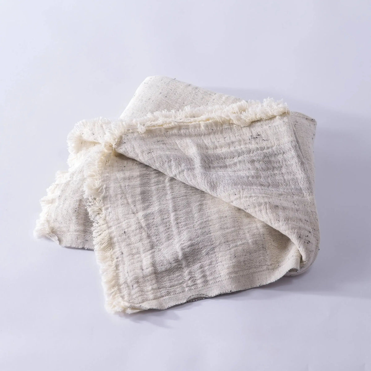 Off-white cotton nope yarn muslin bath towel with dark speckles and frayed edges