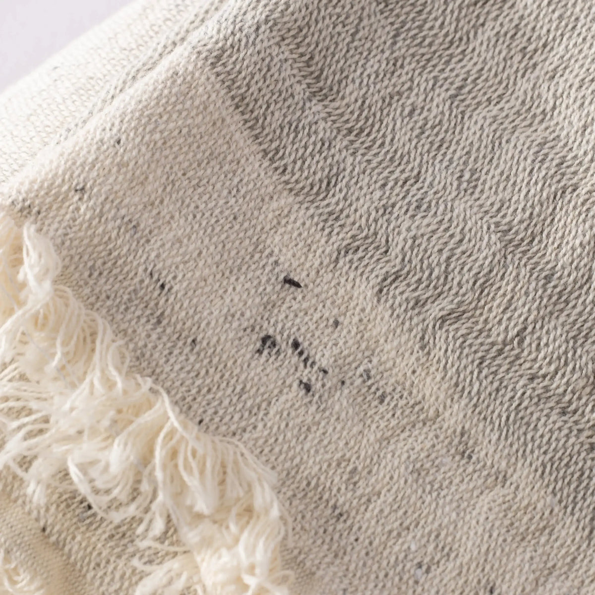 Off-white double-layered muslin bath towel with fringe and dark speckles made of cotton nope yarn