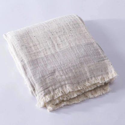 Folded light-colored muslin bath towel made from cotton nope yarn with fringed edges