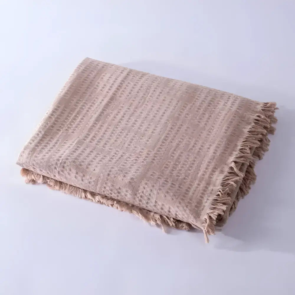 Taupe colored blanket folded on light background