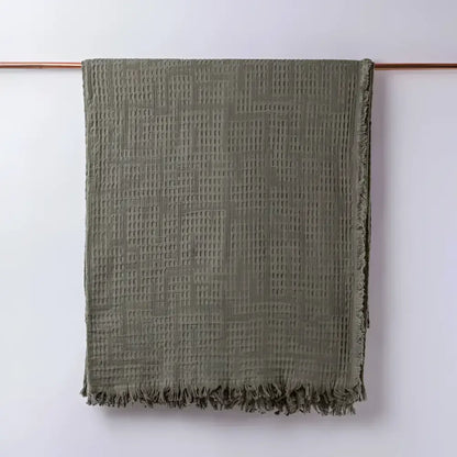 Olive green colored blanket hanging on light background