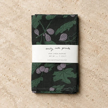 Dark green linen napkins with purple fig designs and hand carved stamp designs wrapped in a white label band set of 2