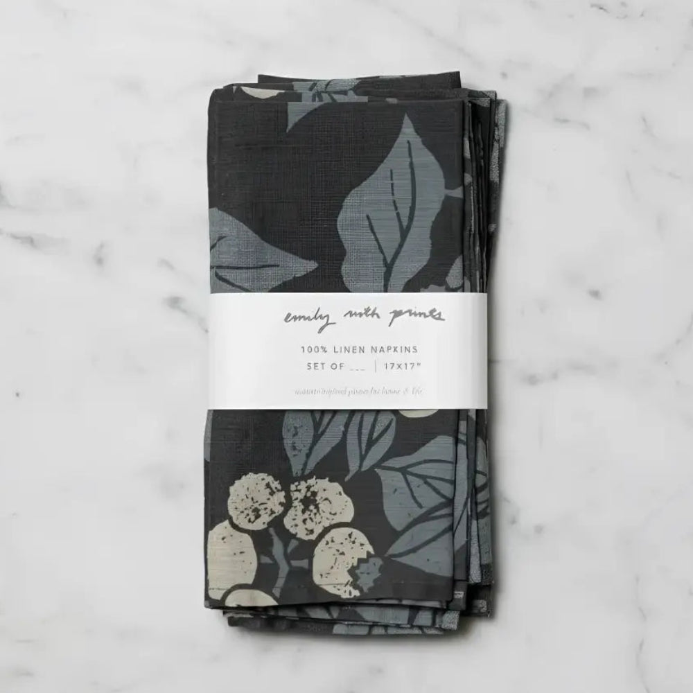 Stack of two dark gray linen napkins with blueberry designs in muted blue and cream tied with a white band