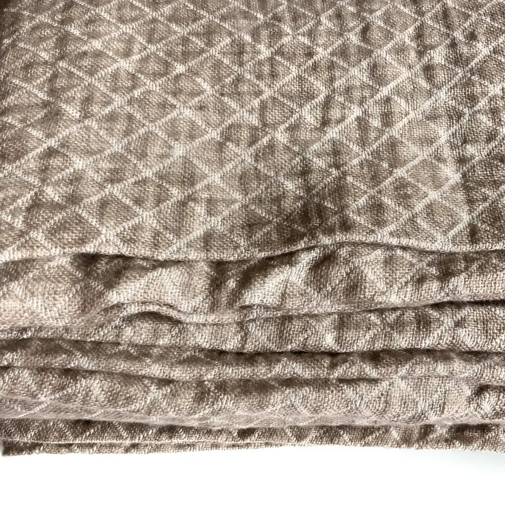 Linen throw blanket with an elegant diamond quilted design in beige and off-white tones.