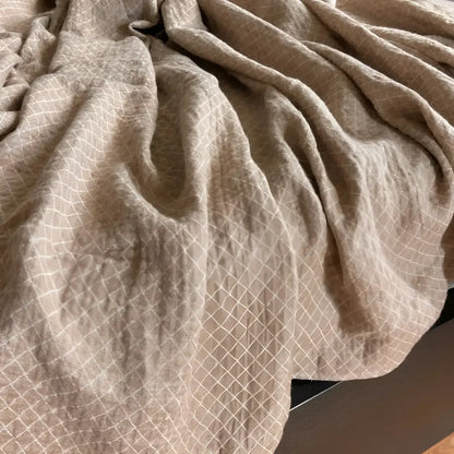 Linen throw blanket with an elegant diamond quilted design in beige and off-white tones.