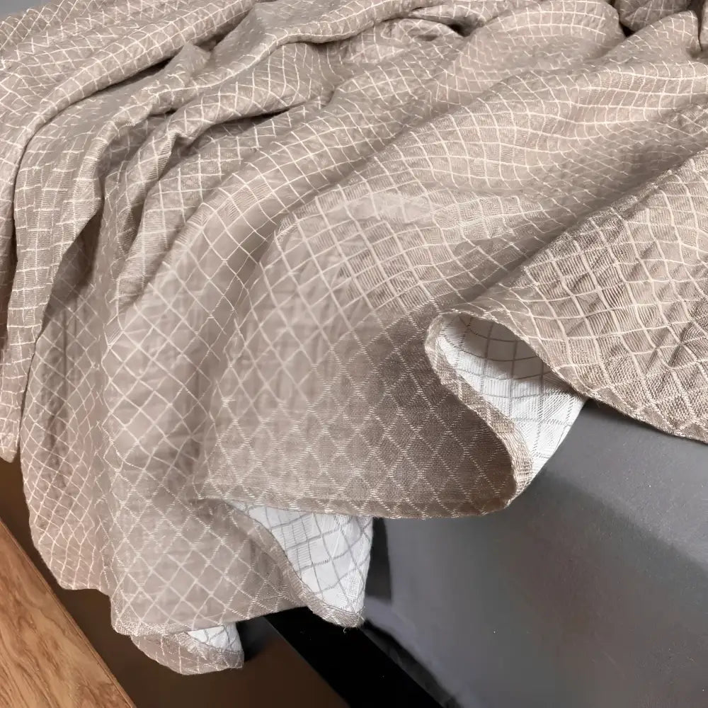 Linen throw blanket with an elegant diamond quilted design in beige and off-white tones.