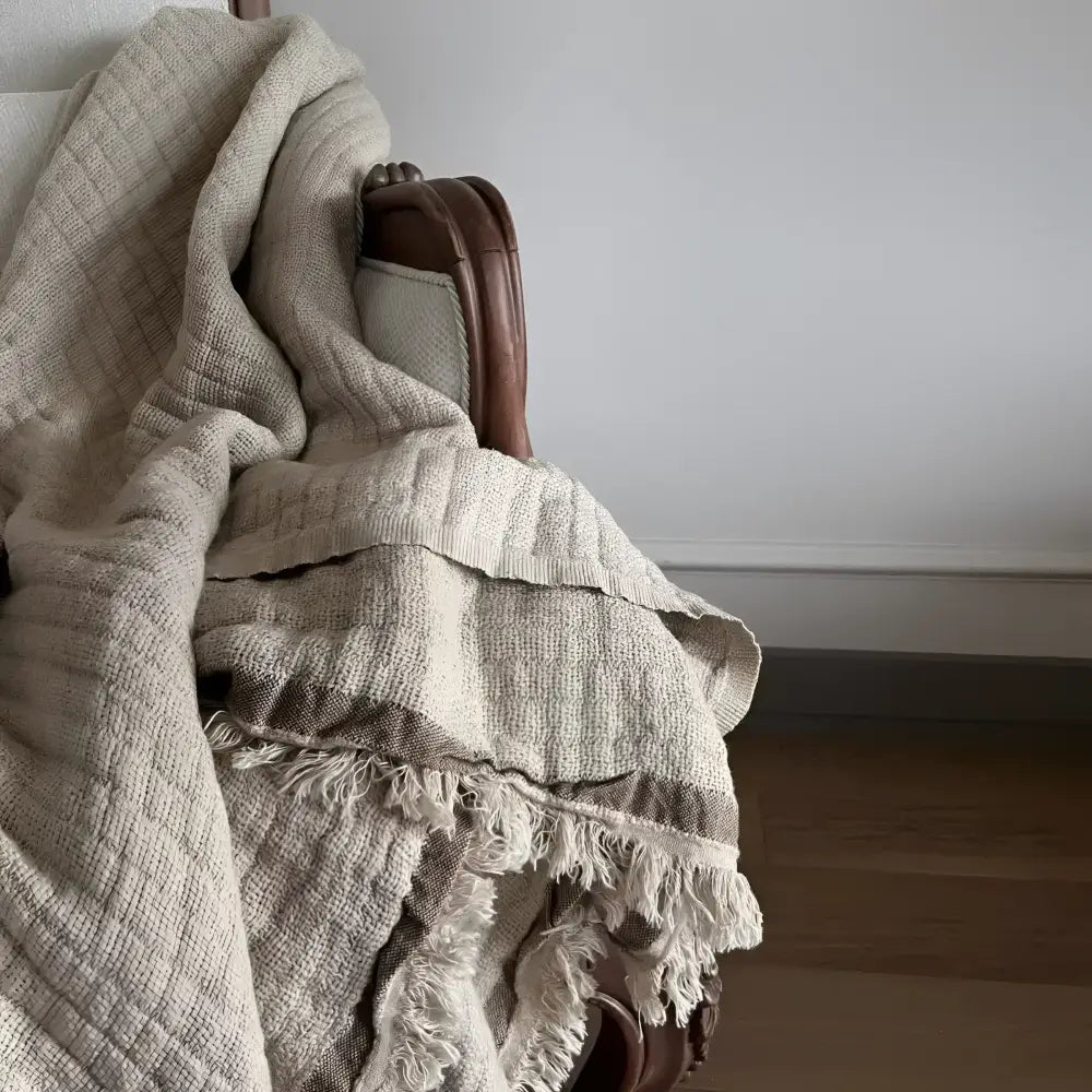 A beige colored linen throw on a white sofa.