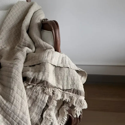 A beige colored linen throw on a white sofa.