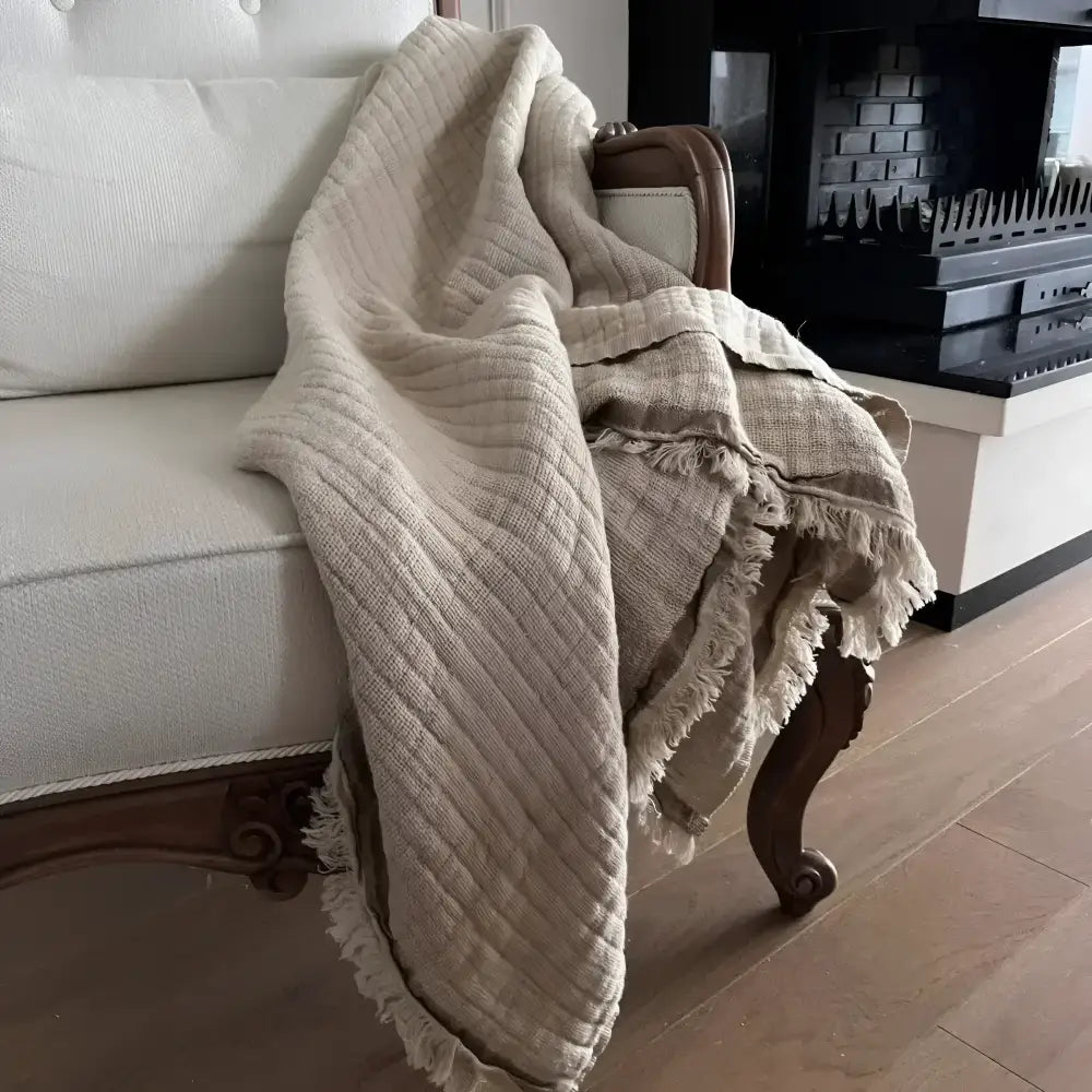 A beige colored linen throw on a white sofa.