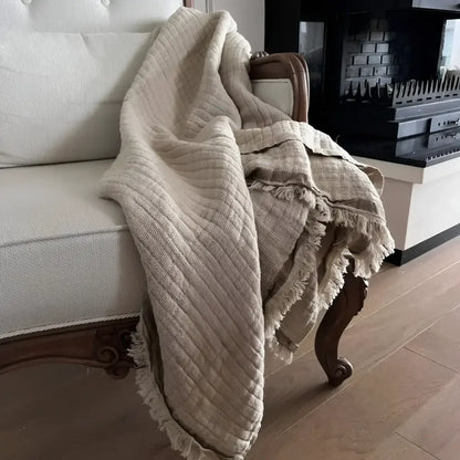 A beige colored linen throw on a white sofa.