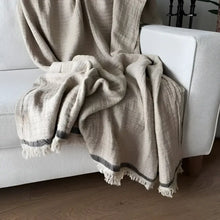A beige colored linen throw on a white sofa.