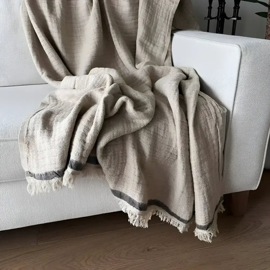 A beige colored linen throw on a white sofa.