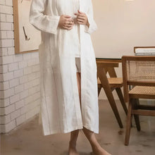 Person wearing a white robe in a room with wooden furniture and a white wall.