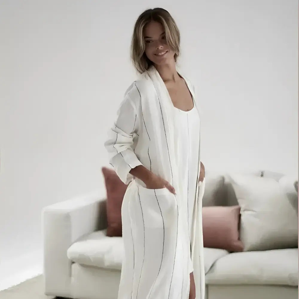 Woman wearing a long white robe standing in a living room.
