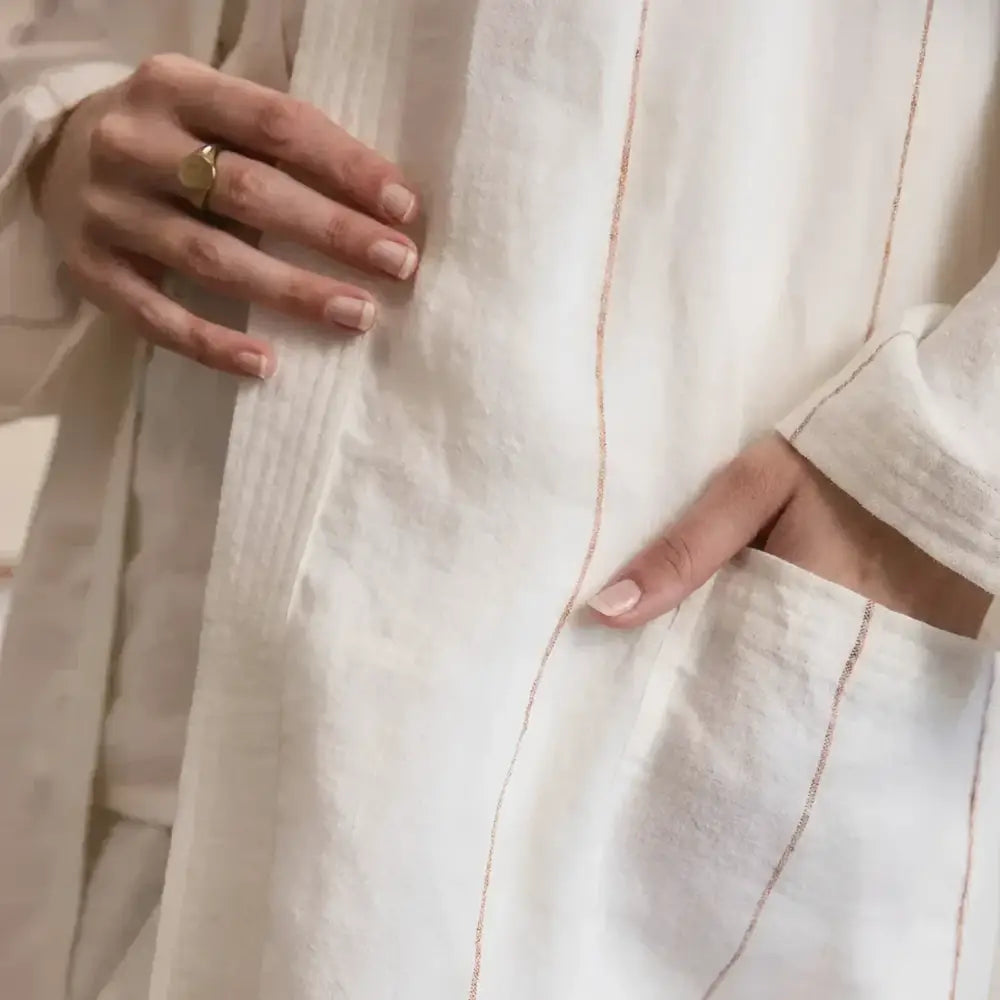 Close-up of a person wearing a light-colored robe with a gold ring.