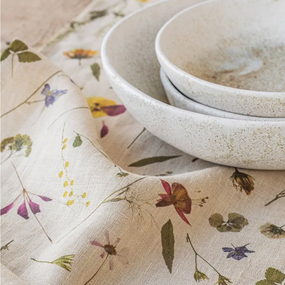 100% Linen tea towel with a natural base color and embellished with botanical prints inspired by pressed flowers. 