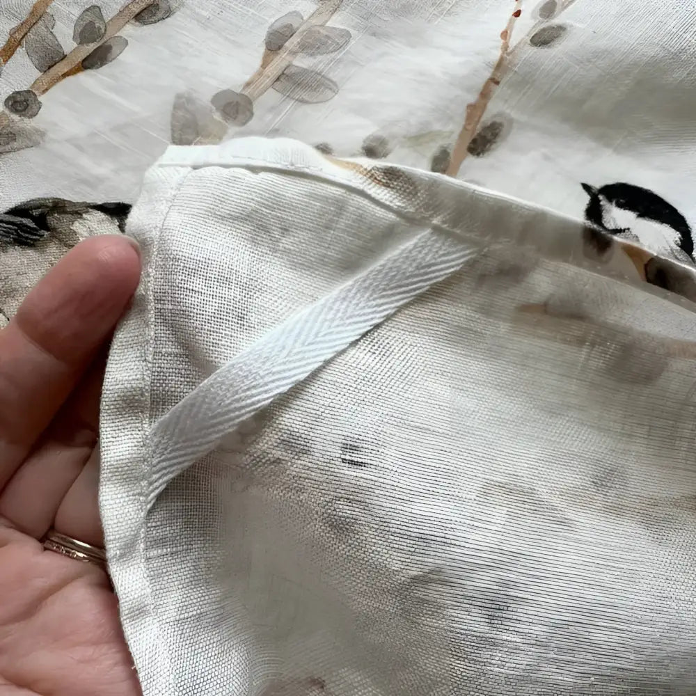 Close-up of a hand holding a piece of fabric with floral patterns.