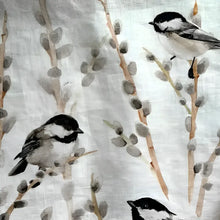 Fabric with bird and branch pattern and a wooden rolling pin on a light background