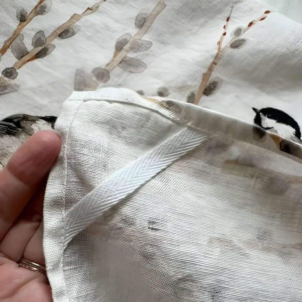 Close-up of a hand holding a piece of fabric with floral patterns.
