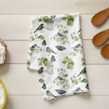 Fabric with nature-themed design on a wooden surface with flour and wooden spoons.