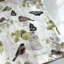 Fabric with nature-themed design featuring birds, butterflies, and plants on a white background.