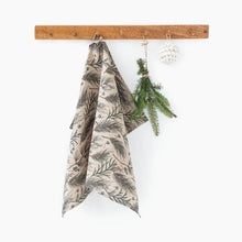 This linen tea towel features a natural colored base with a design print of evergreen foliage and berries.