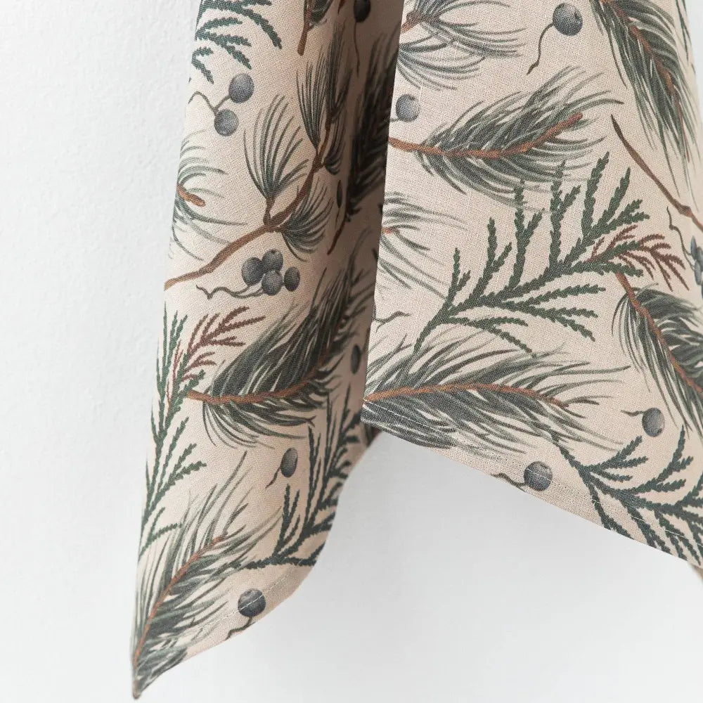 This linen tea towel features a natural colored base with a design print of evergreen foliage and berries.