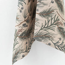 This linen tea towel features a natural colored base with a design print of evergreen foliage and berries.