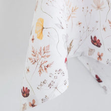 100% linen tea towel with a white base color and has flowers and leaves printed in varying colors throughout.