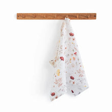 100% linen tea towel with a white base color and has flowers and leaves printed in varying colors throughout.