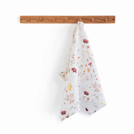 100% linen tea towel with a white base color and has flowers and leaves printed in varying colors throughout.