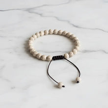 Beige speckled lotus seed mala bracelet with black macrame knot and adjustable cord for easy wear