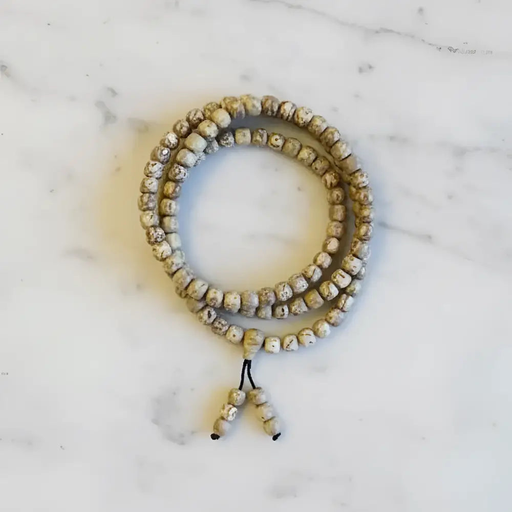 Lotus seed mala bracelet with natural beige and brown beads and a black beaded tassel carrying lotus seeds