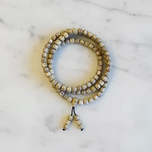 Lotus seed mala bracelet with natural beige and brown beads and a black beaded tassel carrying lotus seeds