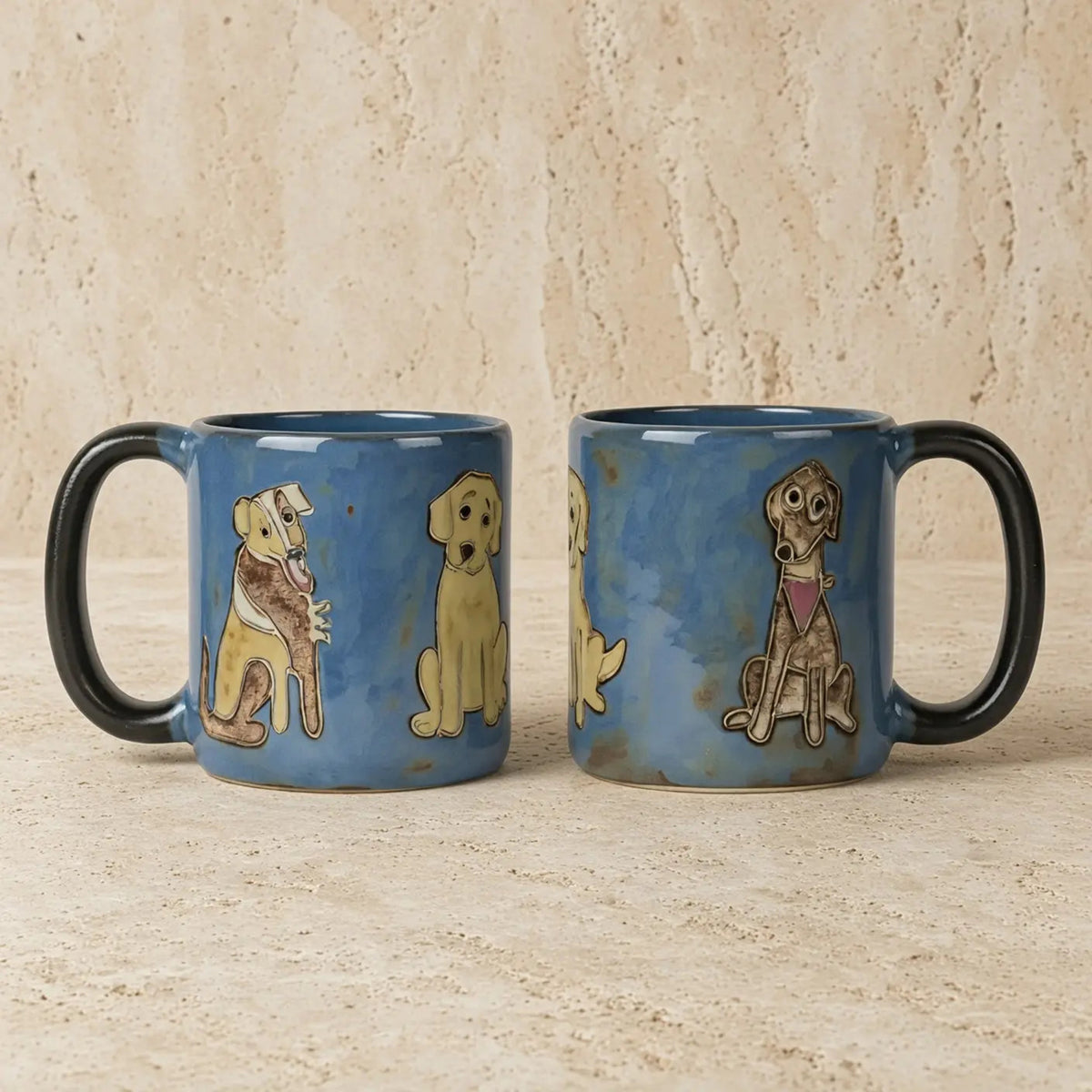 Blue stoneware mugs with black handles hand painted with cartoon dogs by mara ceramica artisans in mexico