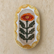 An oval ceramic marigold sgraffito pottery trinket dish with an intricate marigold design and golden-yellow border