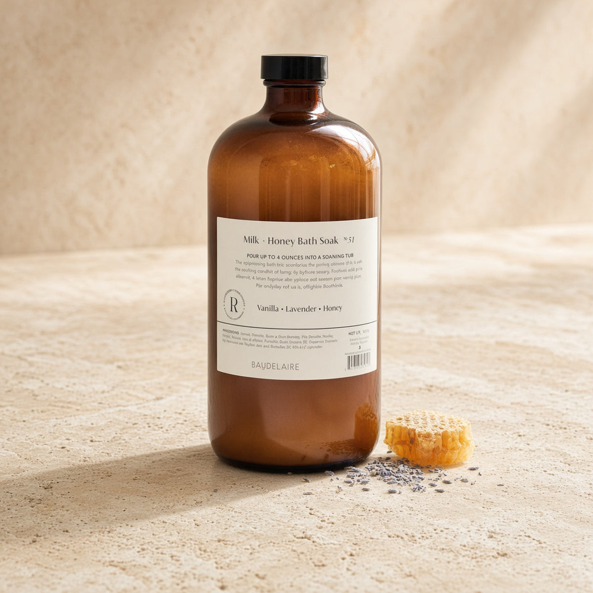 A 40oz bath soak in an amber glass bottle with a black cap labeled milk and honey bath soak by baude laire