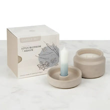 A mindful moments candle set featuring a beige ceramic vessel and saucer with an ombre white to light blue taper candle
