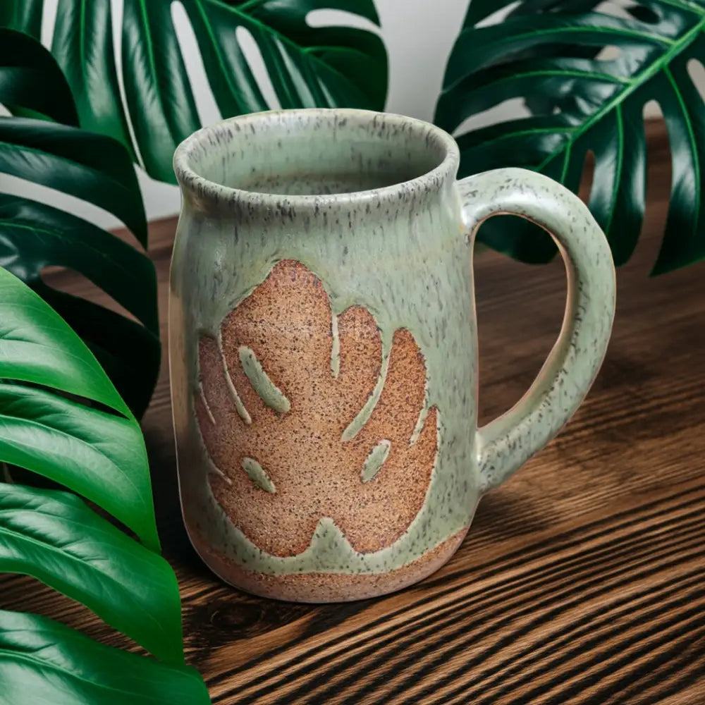 Light green thrown monstera mug with raised reddish-brown Monstera leaf design
